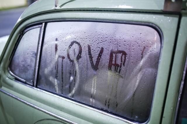 A foggy car window with the word "Love" written on the window